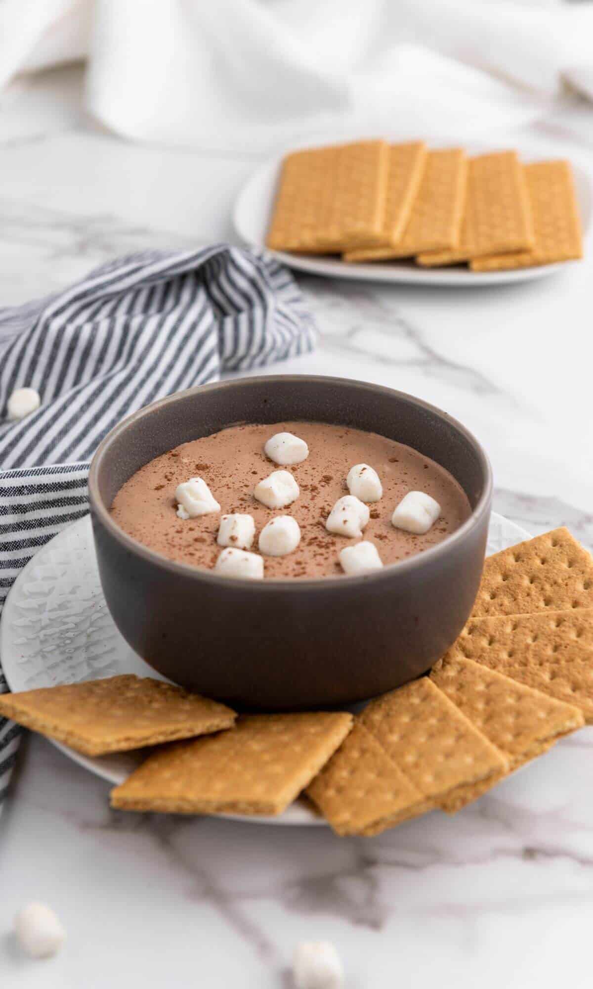 A bowl full of hot cocoa dip with marshmallows on top.