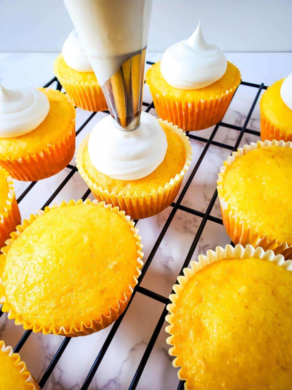 Baked pina colada cupcakes being frosted.