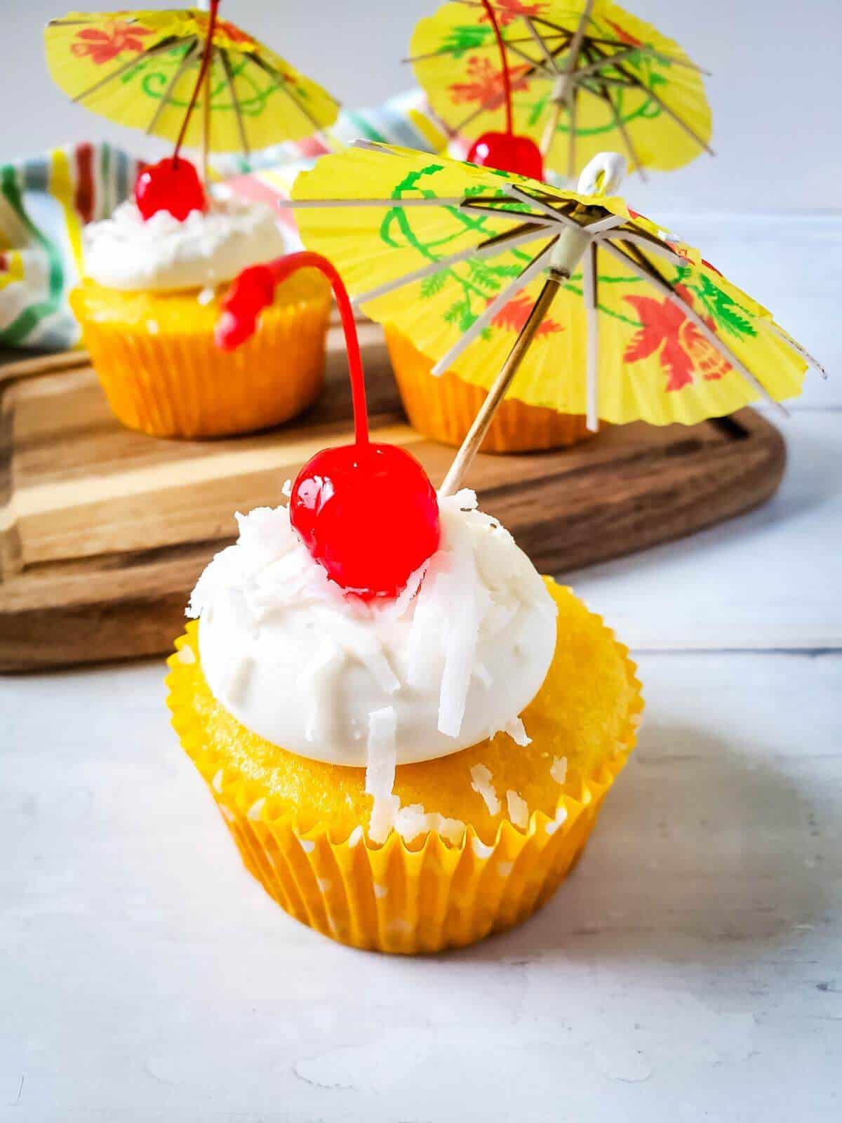 Pina colada cupcakes with tropical umbrellas on them.