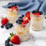 Gluten free overnight oats in glass jars with fruit toppings.